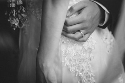 Midsection of bride with groom arm around