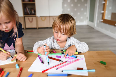 Little boy with sister drawing with felt-tip pens