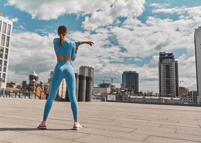 Side view of woman standing on road against cloudy sky