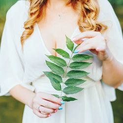 Midsection of woman with leaves standing outdoors