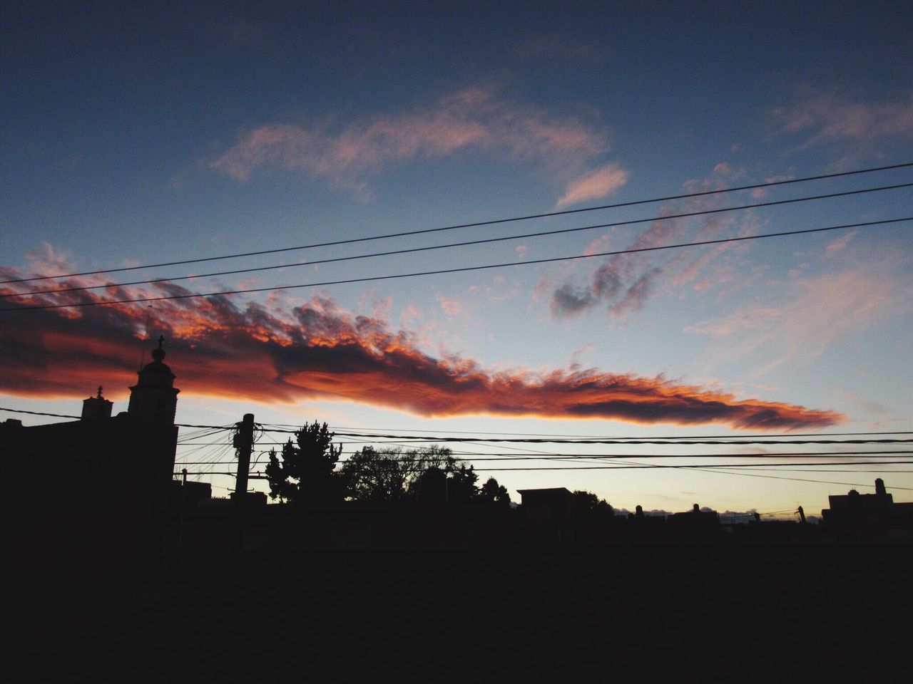 silhouette, sunset, sky, cloud - sky, power line, low angle view, beauty in nature, cloud, scenics, orange color, cloudy, nature, dramatic sky, outline, tranquility, dark, cable, outdoors, tranquil scene, moody sky, no people, idyllic, weather, blue, landscape