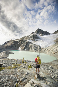 Rear view of person on snowcapped mountain against sky