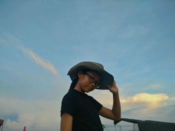 Portrait of girl in sun hat standing against sky