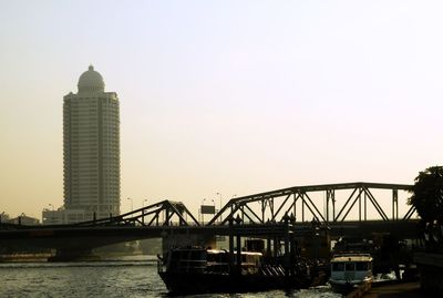 Bridge over river in city against clear sky