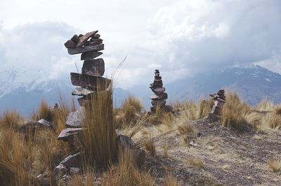 Stone stacks on field against sky