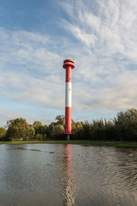 Lighthouse by trees against sky