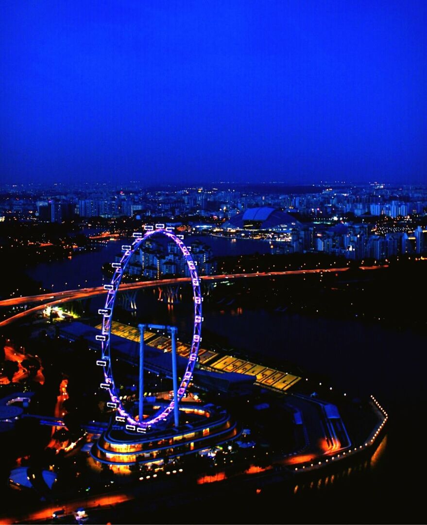 illuminated, night, ferris wheel, city, clear sky, architecture, built structure, cityscape, copy space, building exterior, arts culture and entertainment, amusement park ride, amusement park, city life, transportation, high angle view, blue, modern, travel destinations, capital cities