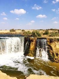 Scenic view of waterfall against sky