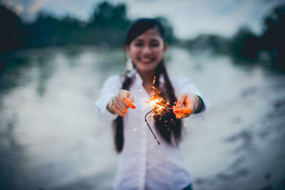 Smiling young woman standing on fire in water