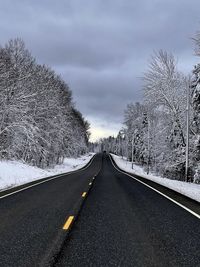 Road amidst bare trees against sky