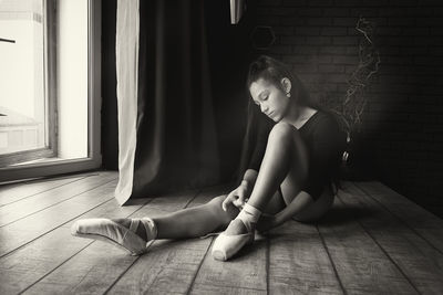 A young gentle and thoughtful ballerina poses in the interior and at the window