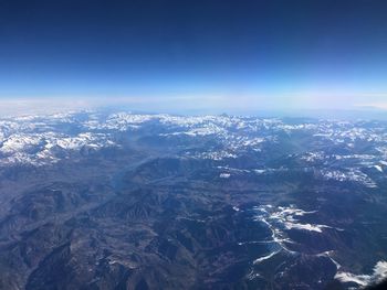 Aerial view of snowcapped mountains against blue sky