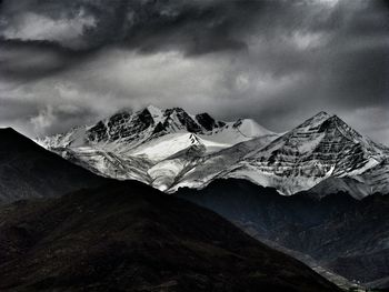 Scenic view of snowcapped mountains against cloudy sky