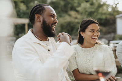 Happy male and female friends laughing during dinner party at cafe