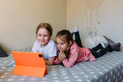 Portrait of smiling boy using digital tablet while sitting on bed at home