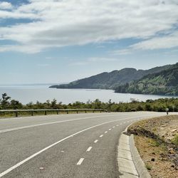 Road passing through mountains against cloudy sky