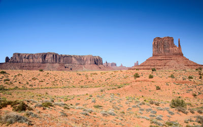 Rock formations on landscape against clear blue sky