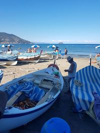 People on beach against clear blue sky