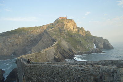 Scenic view of cliff by sea against sky