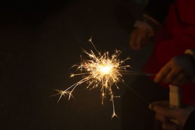 Close-up of hand holding illuminated firework display at night