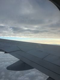 Low angle view of airplane flying against cloudy sky