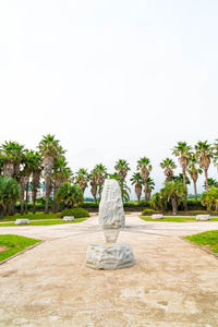 Statue amidst palm trees against clear sky