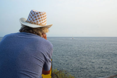 Rear view of man looking at sea against sky