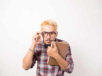 Portrait of young man standing against white background