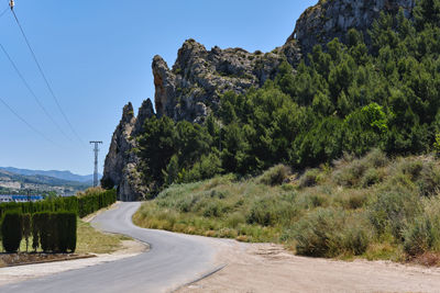 Road by trees against sky