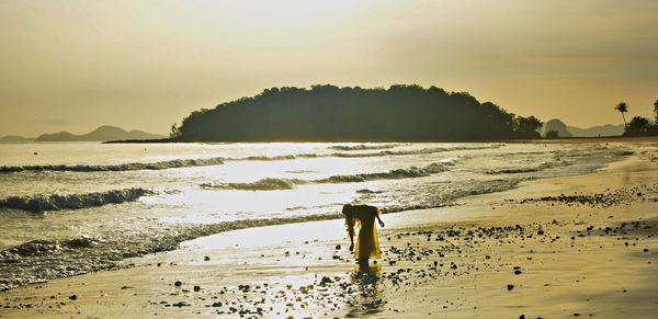 Silhouette man standing on beach against sky during sunset