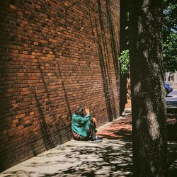 Man sitting against wall in city