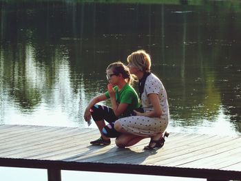 Young couple sitting on pier over lake