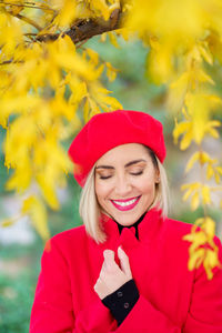 Portrait of smiling young woman standing against plants