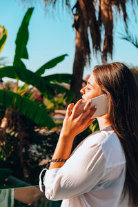 Midsection of woman holding plant against trees