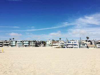 Scenic view of beach by buildings against blue sky