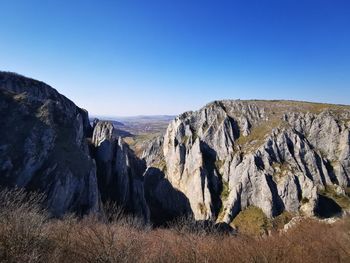 Panoramic view of rocky mountains against clear blue sky