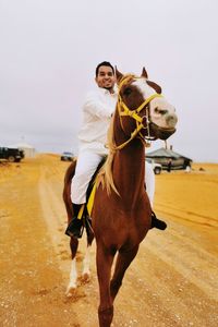 Man riding horse and behind him tents.