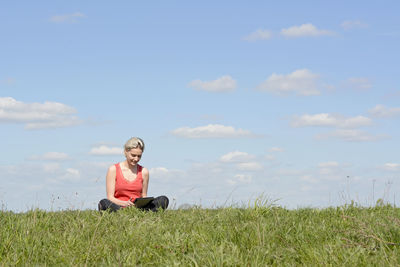 Man sitting on field against sky