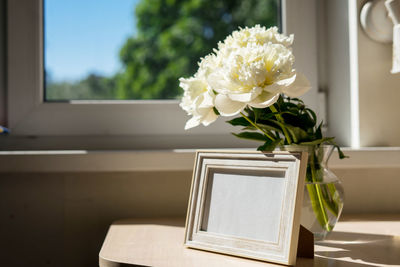 Portrait white picture frame mockup on wooden table.