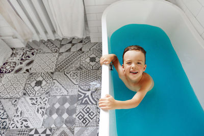 Cute child bathing in blue water in bathtub