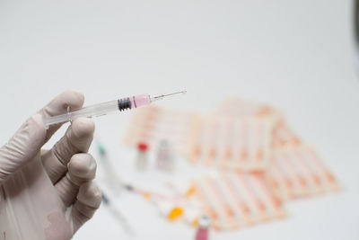 Cropped hand of doctor holding syringe over white background