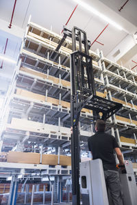 Worker operating forklift in factory warehouse