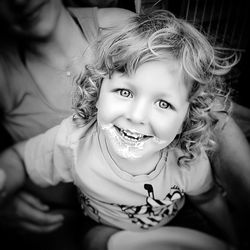 Portrait of messy boy smiling while sitting with mother at home