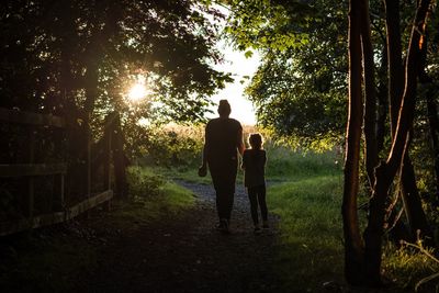 Rear view of mother and daughter walking on tree