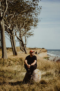 Young man looking at camera while sitting on land