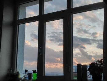 Silhouette cityscape against sky seen through window