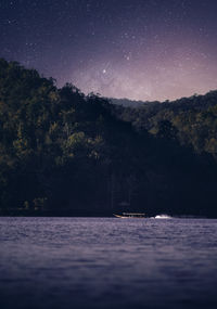 Scenic view of river by forest against sky at night