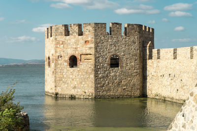 Old building by sea against sky