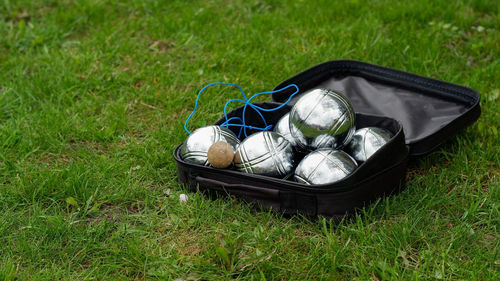 Petanque set with six metal balls in a black case on green grass. play in your own garden.