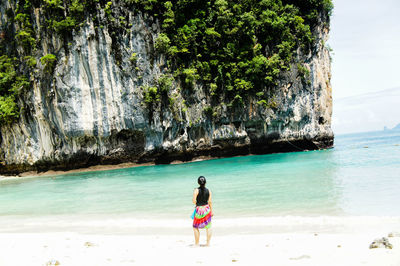 Full length of shirtless young woman standing on beach